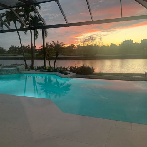 Pool cage enclosure in Naples, Florida featuring a stunning lakefront sunset view and premium aluminum craftsmanship.
